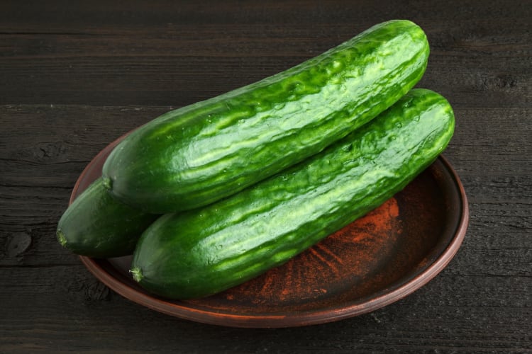Three whole cucumbers on a wooden plate