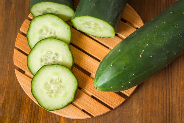 Whole and sliced cucumbers on a board