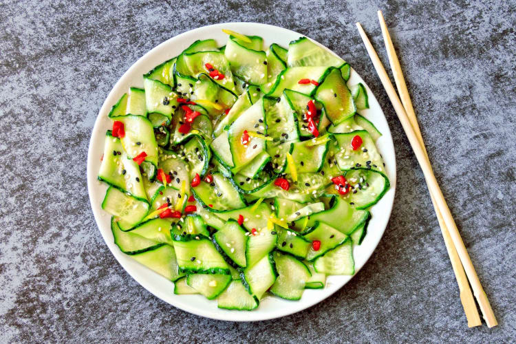 An Asian-style cucumber salad with chopsticks next to it