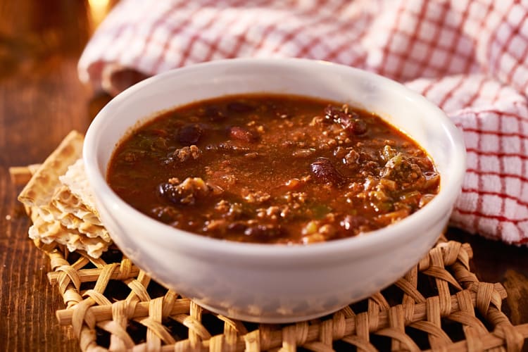 Chili in a white bowl, in front of a dish cloth