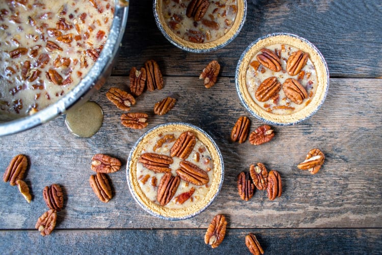 Uncooked mini pecan pies next to a bowl of filling