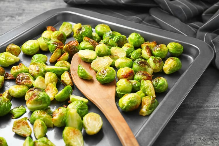 Roasted Brussels sprouts on a pan with a spoon in the middle of them