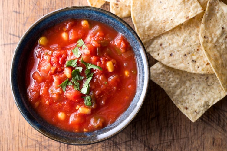 A bowl of salsa next to tortilla chips