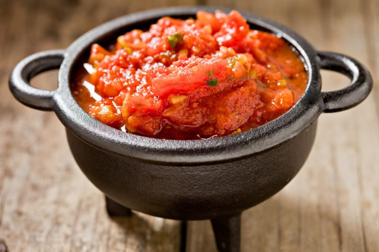 A cast iron pot filled with salsa