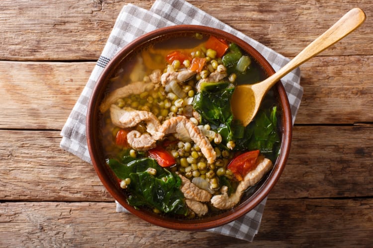 A bowl of stew with spinach, chicken and lentils