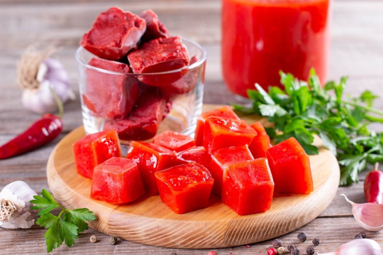 Frozen tomato paste in cubes on a wooden board