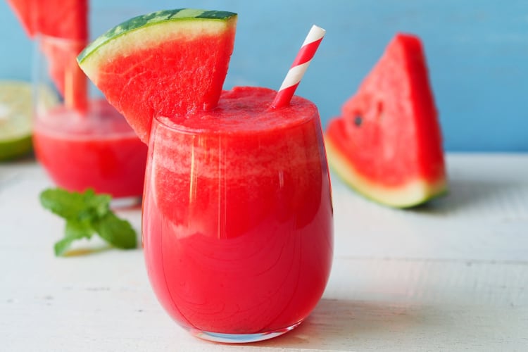 Watermelon smoothies next to a slice of watermelon