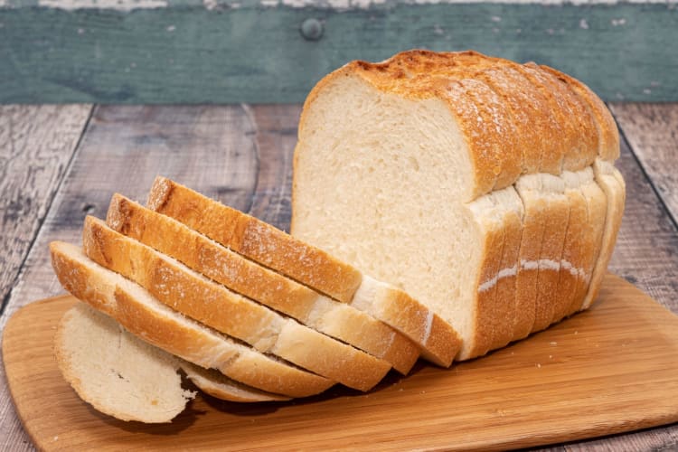 A whole sliced loaf of bread on a wooden board.