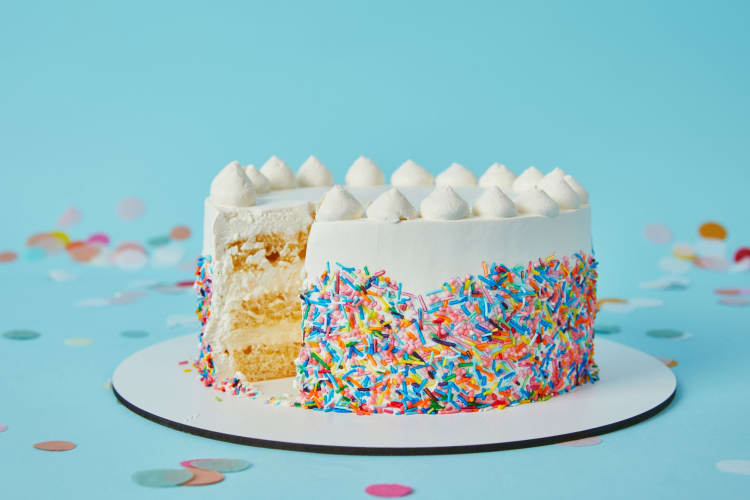 A colorful birthday cake with a large slice carved out of it.