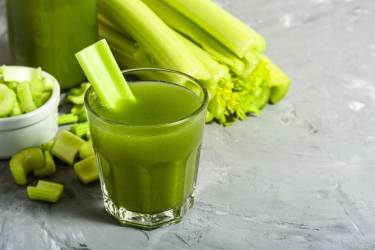 A glass of celery juice next to celery