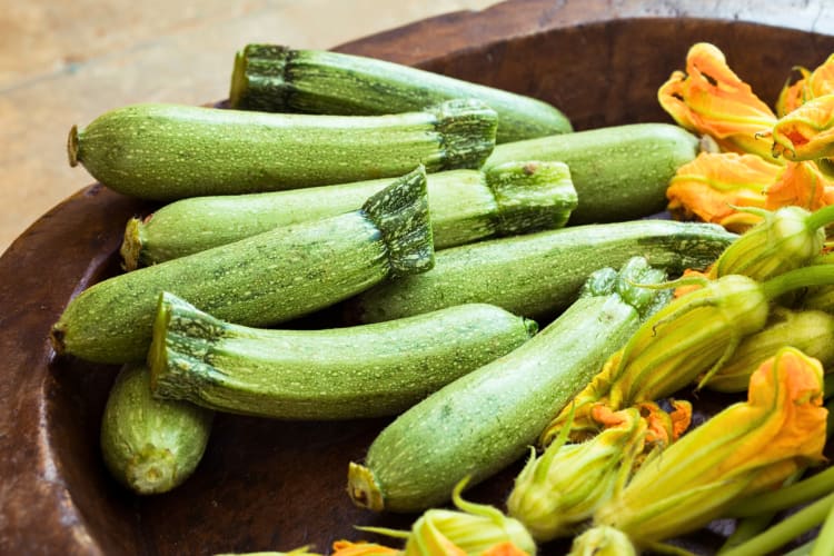 Many zucchini in a bowl with flowers