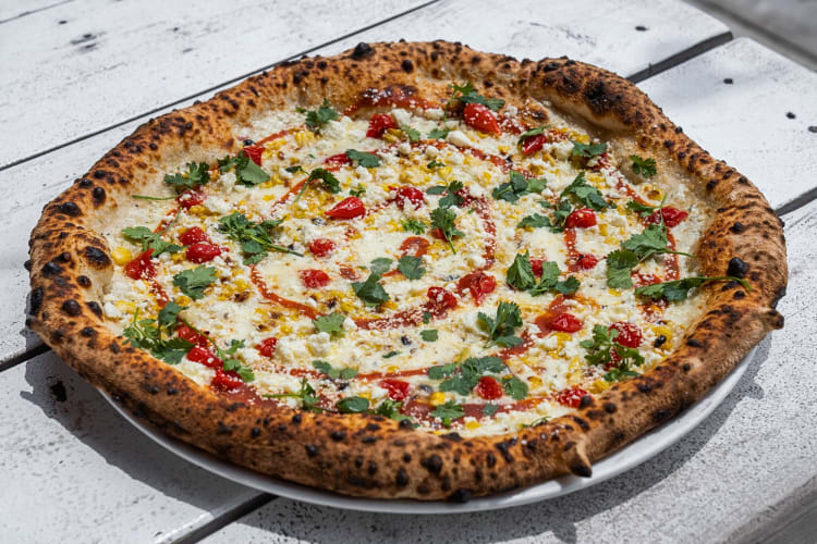 Pizza topped with herbs, cheese and tomatoes, from Cane Rosso