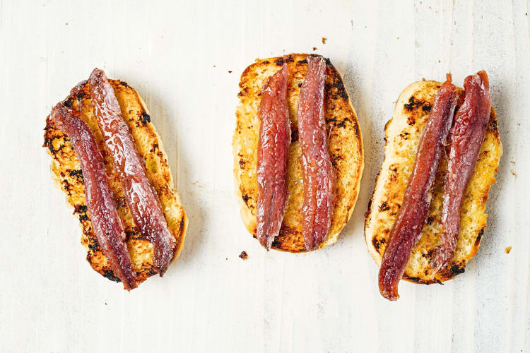 Aerial view of three slices of toast, each with two anchovies on them