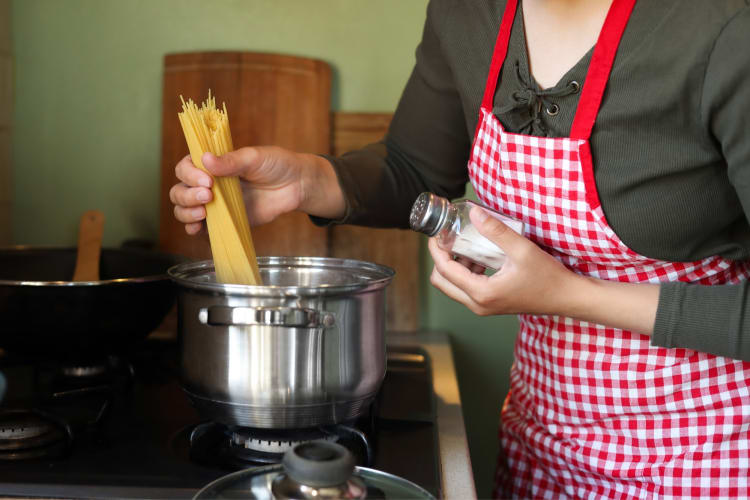 A person putting capellini into a pot