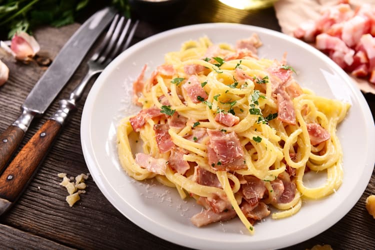 Carbonara on a plate next to a knife and fork