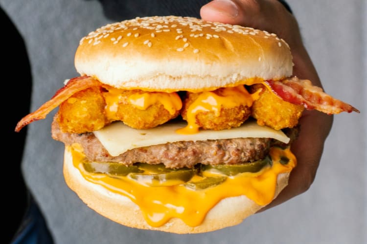 A burger with hash browns and jalapeños