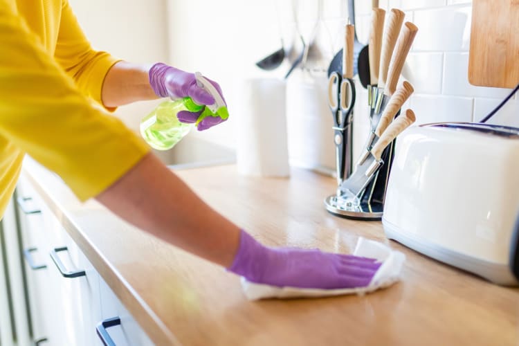 A person disinfecting a kitchen counter