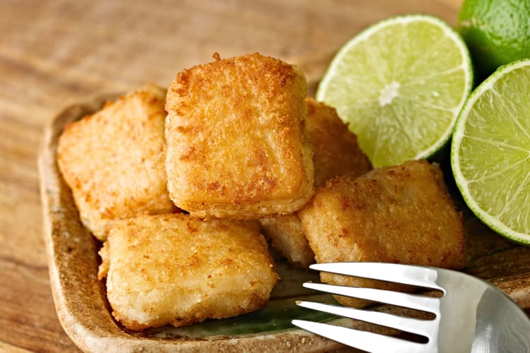 Close-up of fish nuggets, a traditional Seville food, next to lemon wedges