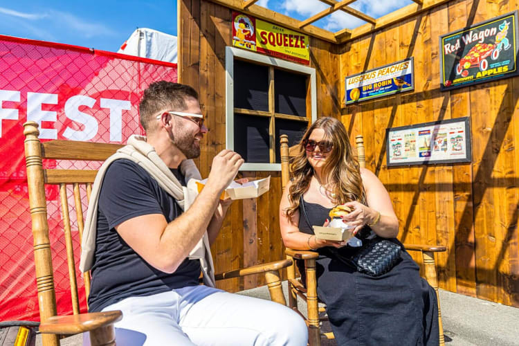 Two people sitting and eating burgers at ChainFEST NYC