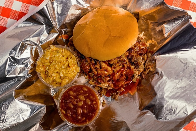 Aerial shot of a pulled pork sandwich with side sauces from Charlie Vergos' Rendezvous