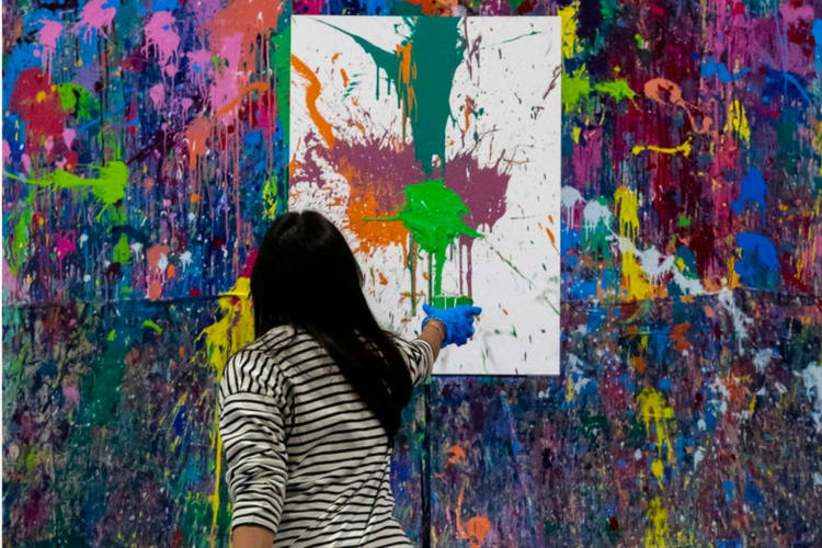 A person throwing colorful paint at a canvas