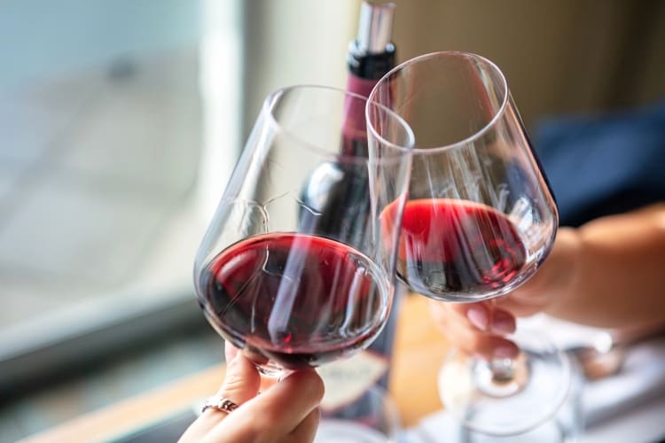 Two hands clinging two glasses of red wine