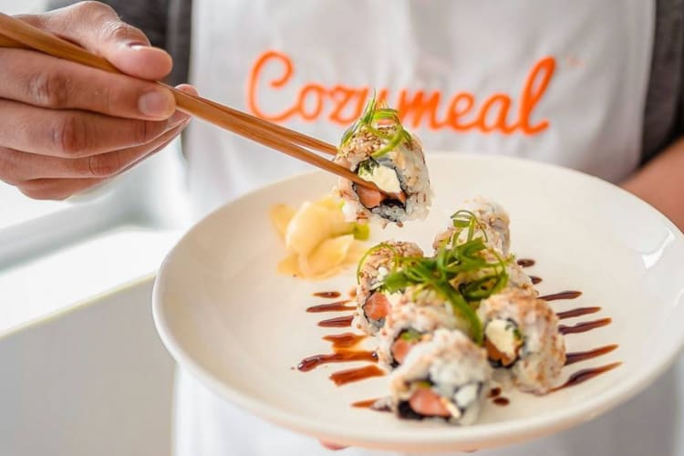 a chef holding a plate of sushi