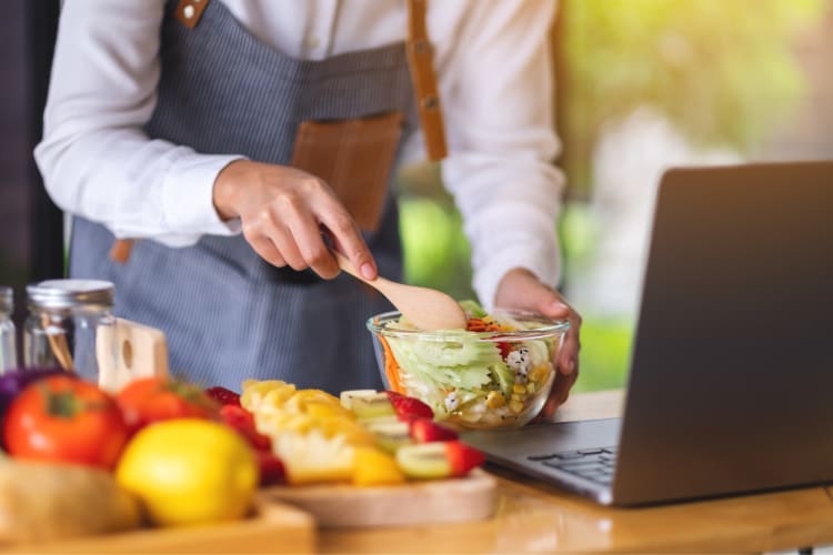 A chef teaching an online cooking class and making a salad