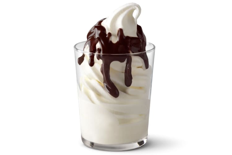 A soft serve sundae in a glass with chocolate sauce