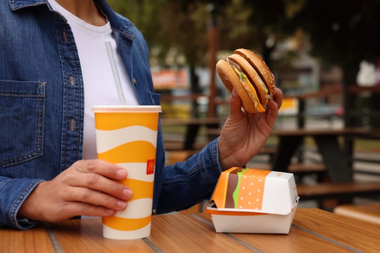 A person eating a burger with McDonald's