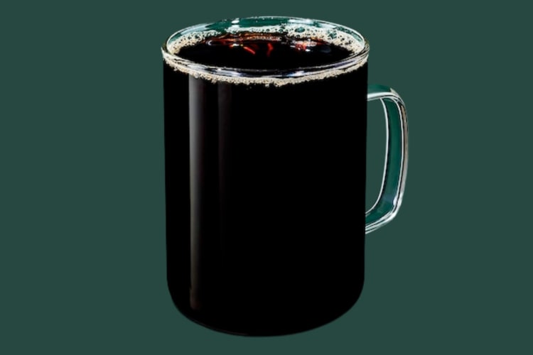 A glass mug with black coffee on a dark green background