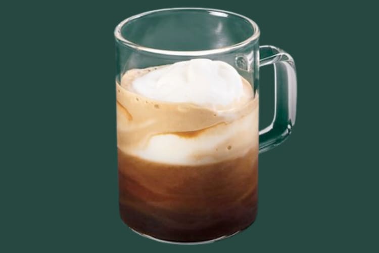 A glass mug with espresso and milk foam