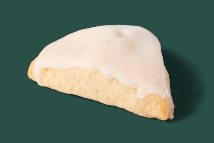 A scone with vanilla icing on a green background