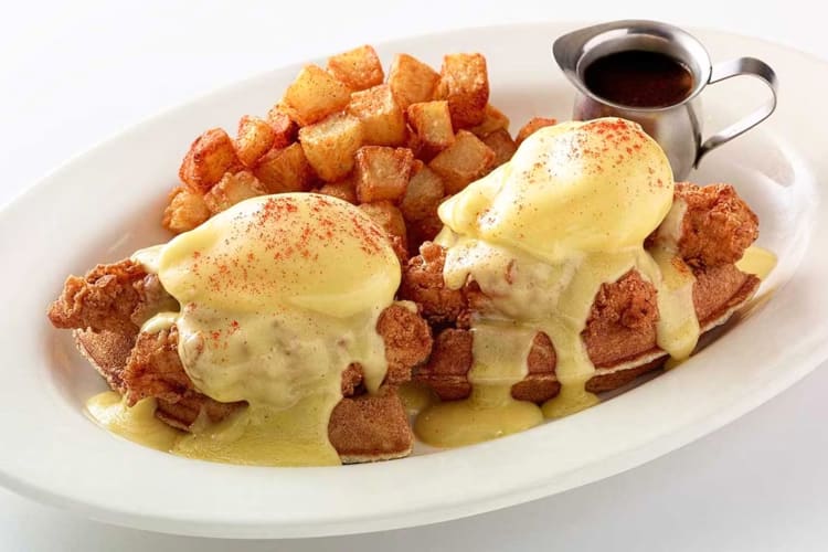 A plate of fried chicken and waffles with eggs Benedict and home fries