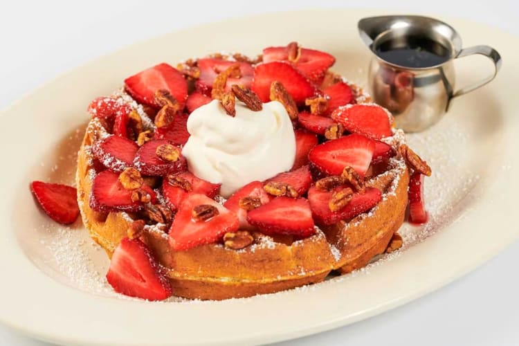 A Belgian waffle with strawberries and whipped cream
