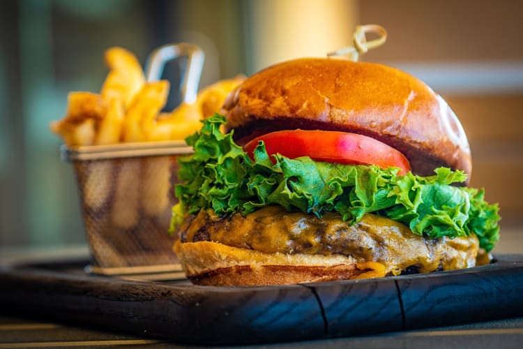 Cheese burger in front of a tray of chips