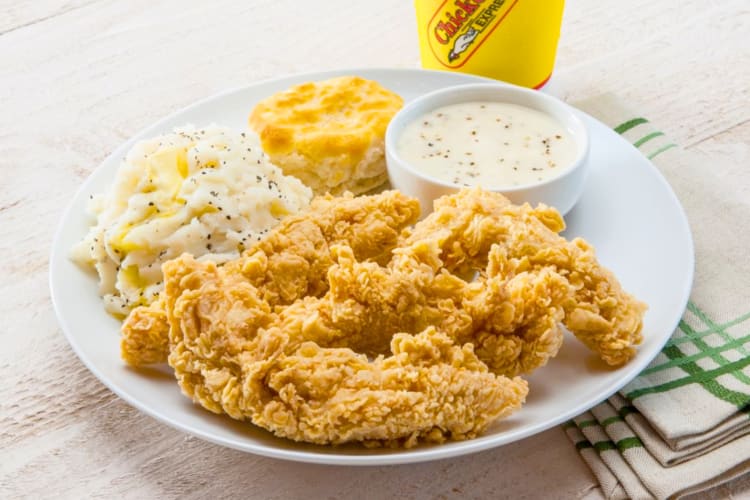 A plate with fried chicken, mashed potatoes, a biscuit and gravy