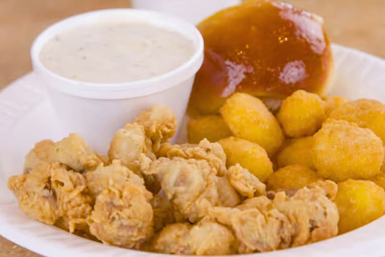 Fried livers on a plate with a bread roll, corn nuggets and gravy
