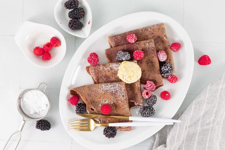 Aerial view of four chocolate crêpes topped with fruit, as a breakfast food idea