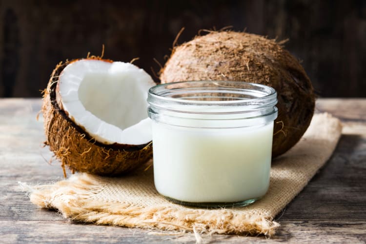 Fresh coconuts next to coconut milk in a glass