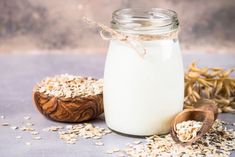 Oat milk in a glass surrounded by fresh oats