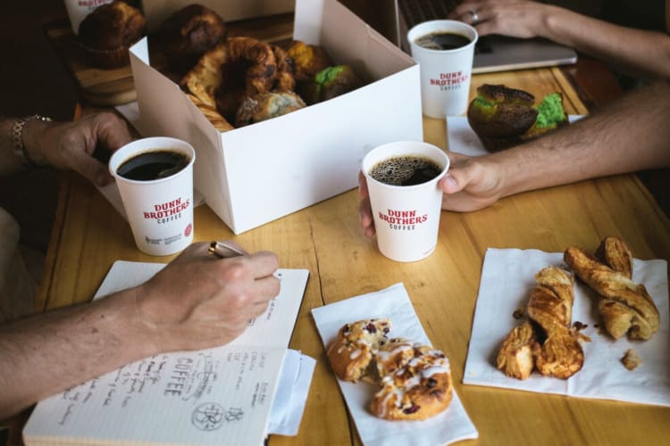 People at a table with coffee and pastries