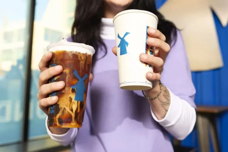 A person holding an iced coffee and a hot coffee in takeout cups