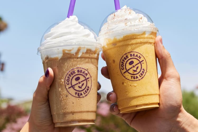 Two people holding blended coffee drinks in plastic takeout cups