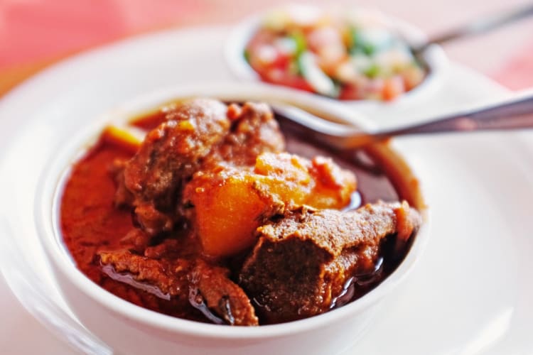 Lamb curry in the foreground with toppings in the background