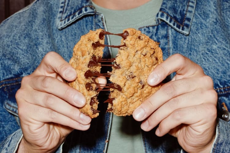 Person's hands breaking apart a chocolate chip cookie