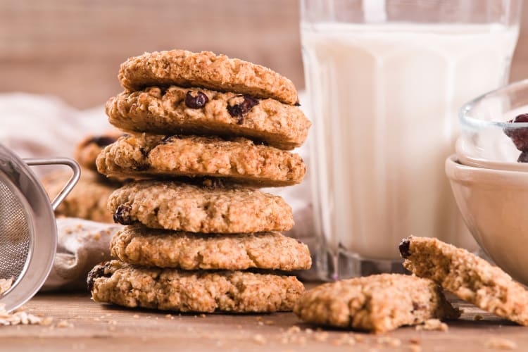A stack of oatmeal cookies next to a glass of milk