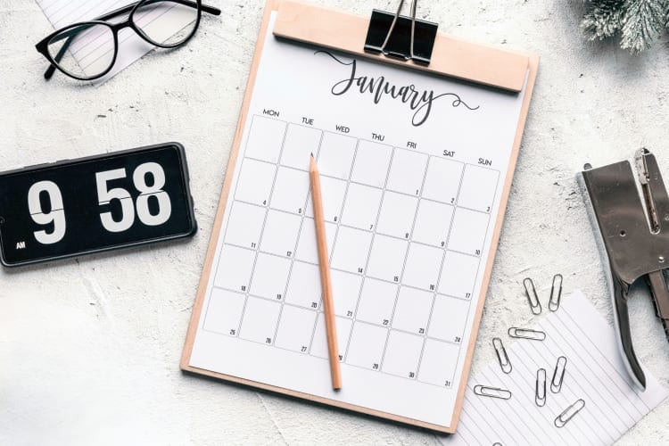 A calendar next to stationary and a phone showing the time
