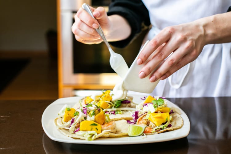 Chef pouring sauce over a freshly-cooked meal