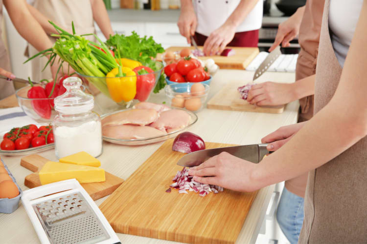 Friends chopping onions while taking a cooking class